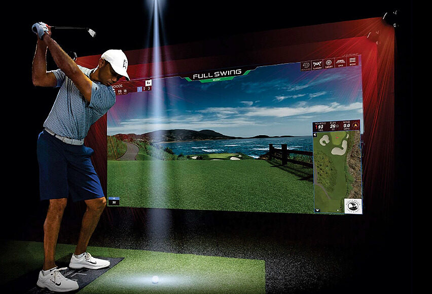 A golfer in a blue outfit and white cap is preparing to swing inside a high-tech golf simulator. _ Pure AV Luxury Home Automation.jpg